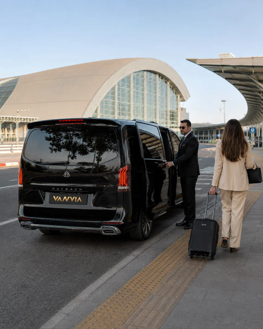 A Vanvia chauffeur opening the vehicle door to welcome a passenger with a rolling suitcase at Izmir Adnan Menderes Airport