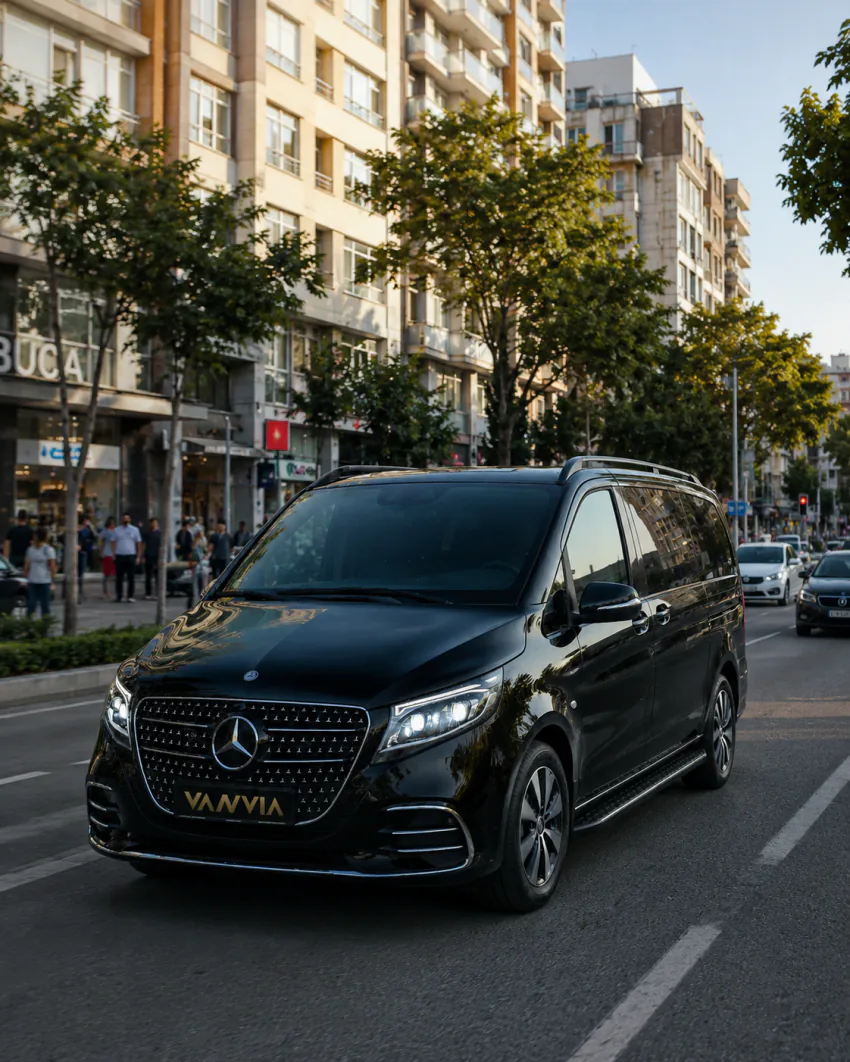 A black Vanvia VIP vehicle driving along a busy street with a sign reading "BUCA" visible, for an Izmir Airport Buca transfer