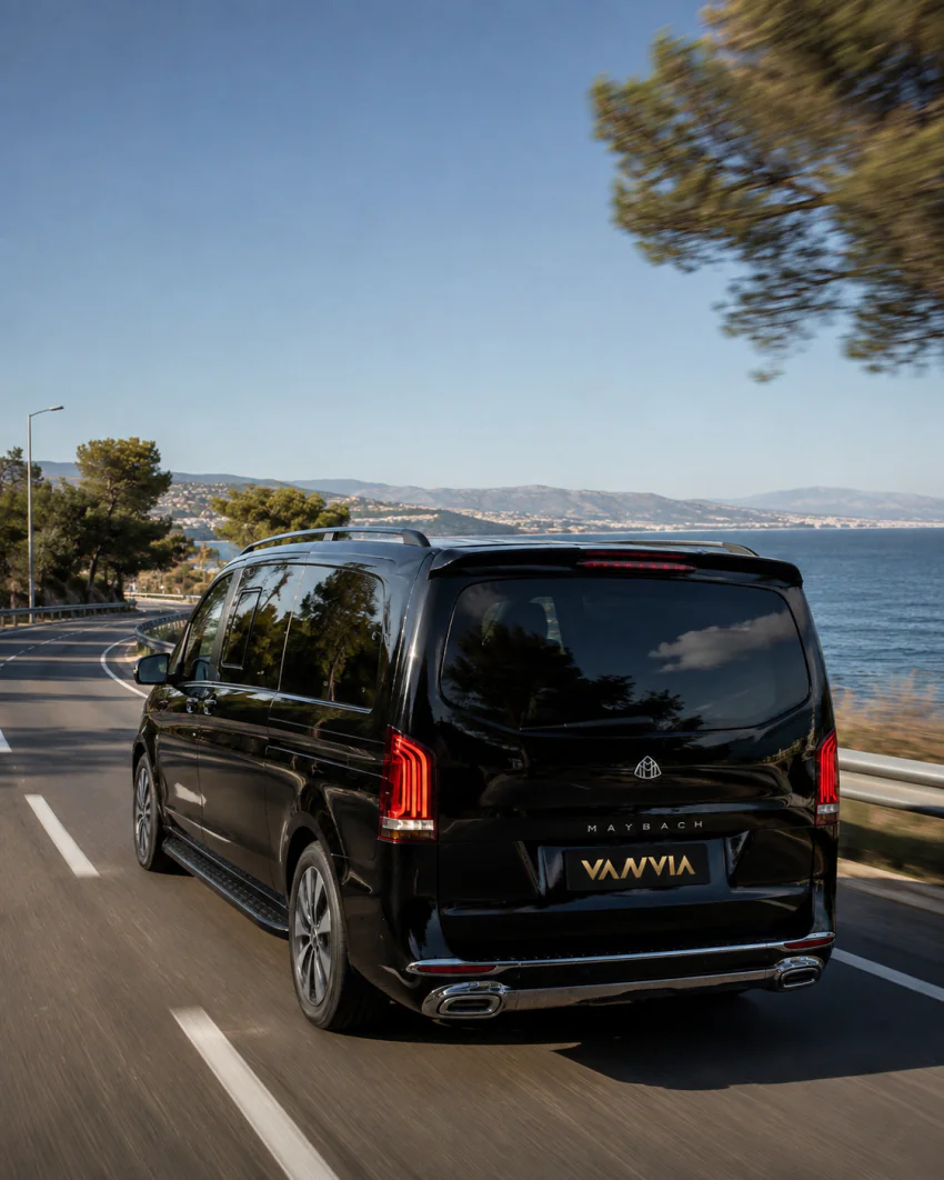 Black Vanvia VIP transfer vehicle driving along a North Aegean coastal road