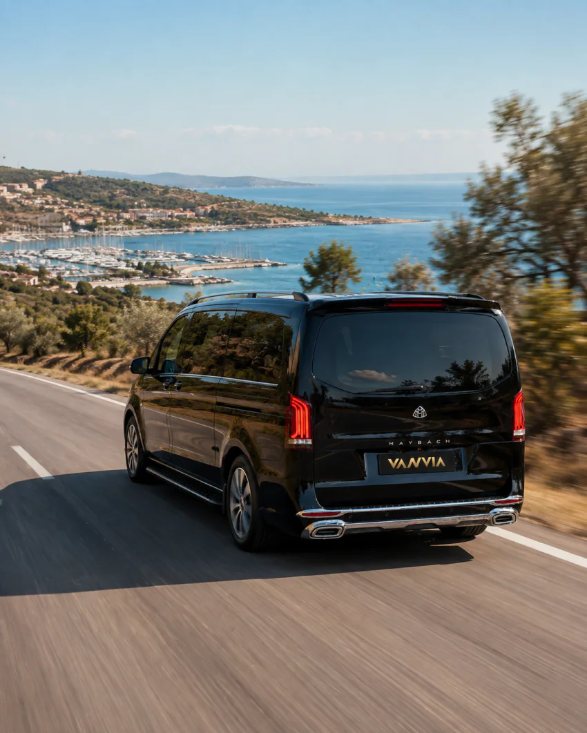 The Vanvia Vito making its way along a coastal road through olive trees, with a marina visible in the distance
