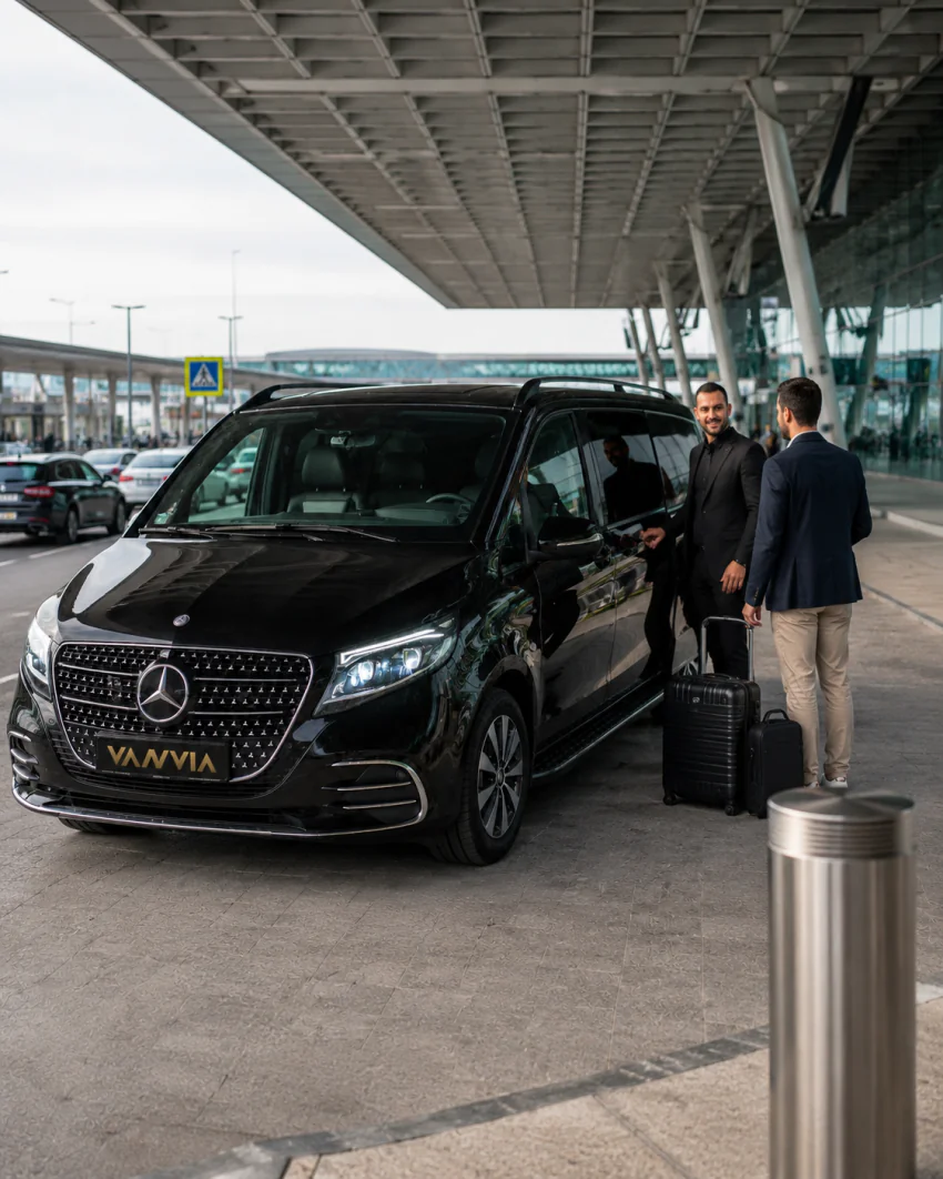 Vanvia chauffeur greeting a traveler with luggage at the ADB Adnan Menderes Airport terminal curb