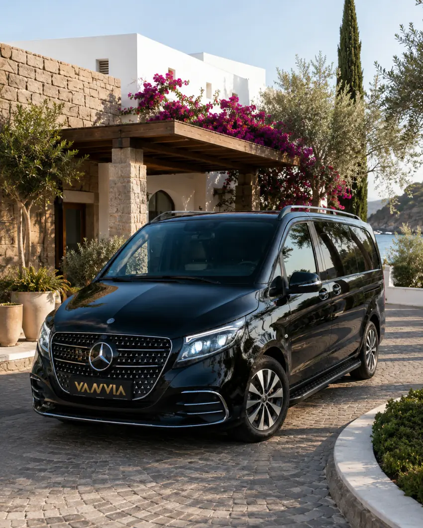 A black Vanvia VIP transfer vehicle waiting for its guest at a whitewashed Bodrum resort hotel entrance with a sea view