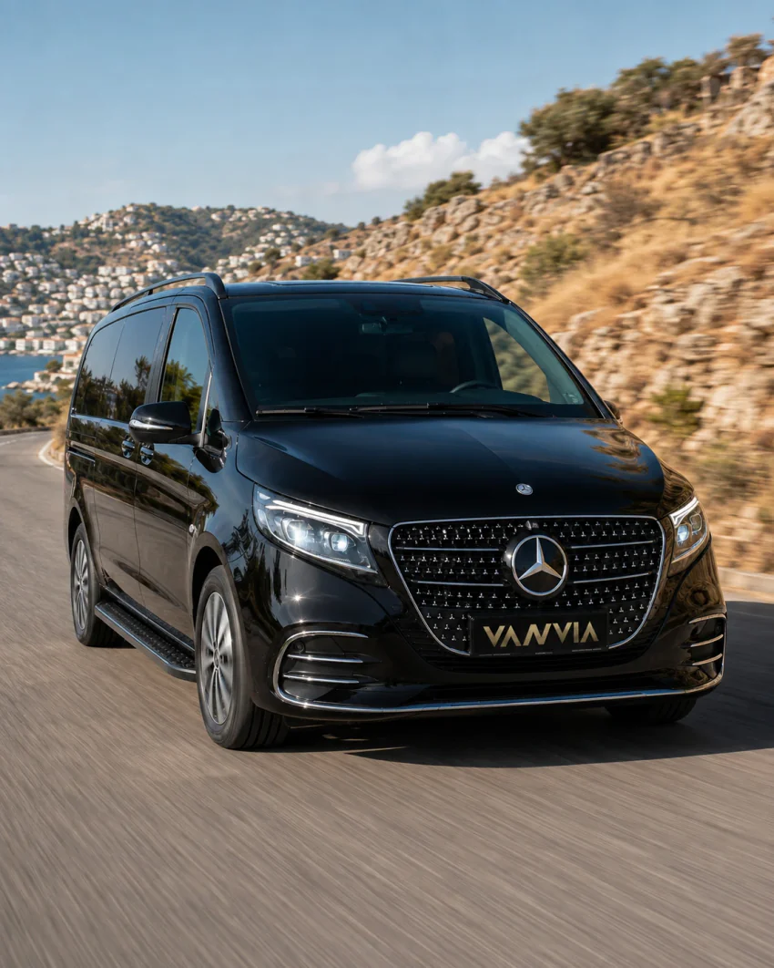 A black Vanvia VIP transfer vehicle driving along a Bodrum peninsula coastal road with a sea view