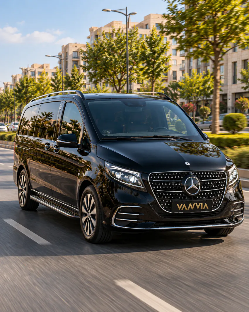 Gaziantep VIP transfer: açık renkli taş cepheli apartmanlar ve ağaçlarla çevrili geniş bir bulvarda ilerleyen siyah Vanvia aracının ön çapraz görünümü