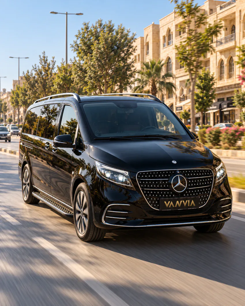 Şanlıurfa VIP transfer: bal rengi taş cepheli binalar ve ağaçlarla çevrili geniş bir caddede ilerleyen siyah Vanvia aracının ön çapraz görünümü