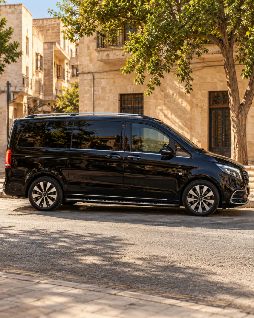 Şanlıurfa'da taş cepheli bir sokakta, ağaç gölgesinde park etmiş siyah Vanvia VIP transfer aracının yandan görünümü