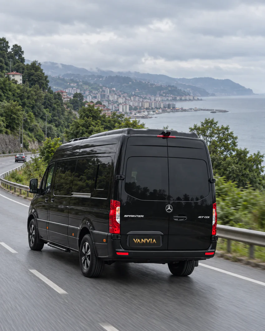 Trabzon çevresinde Karadeniz kıyısı ve yeşil yamaçlar boyunca uzanan şehir çıkış yolunda ilerleyen siyah Vanvia VIP transfer aracı