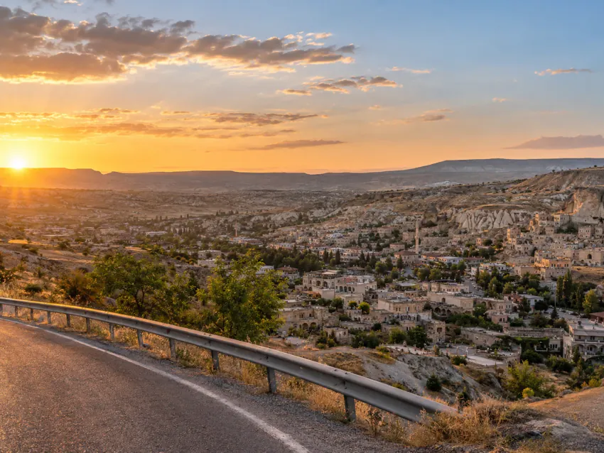 Ürgüp'ün tarihi taş kasabasının alacakaranlıkta yükseklikten görünümü; taş konaklar, teraslar, bir minare ve kayalık bir yamaca oyulmuş yapılar; araç görünmüyor