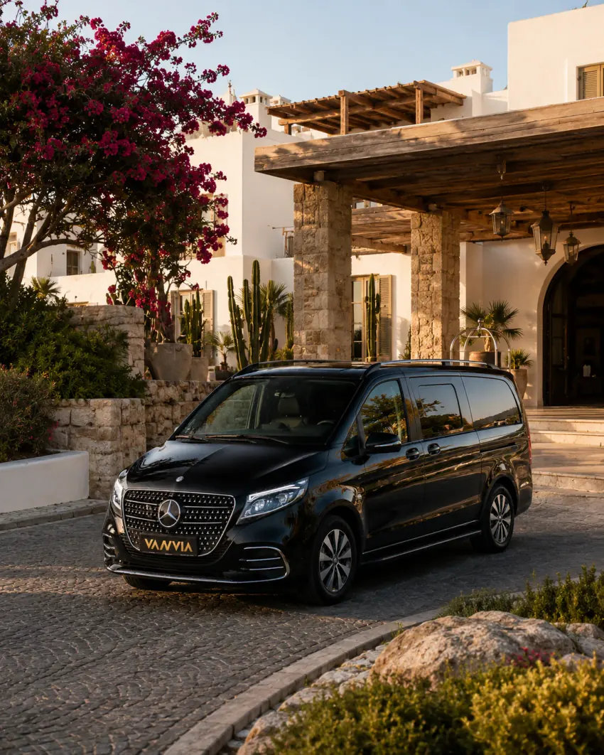 A black Vanvia VIP transfer vehicle waiting at a generic Yalıkavak resort entrance surrounded by bougainvillea and cacti